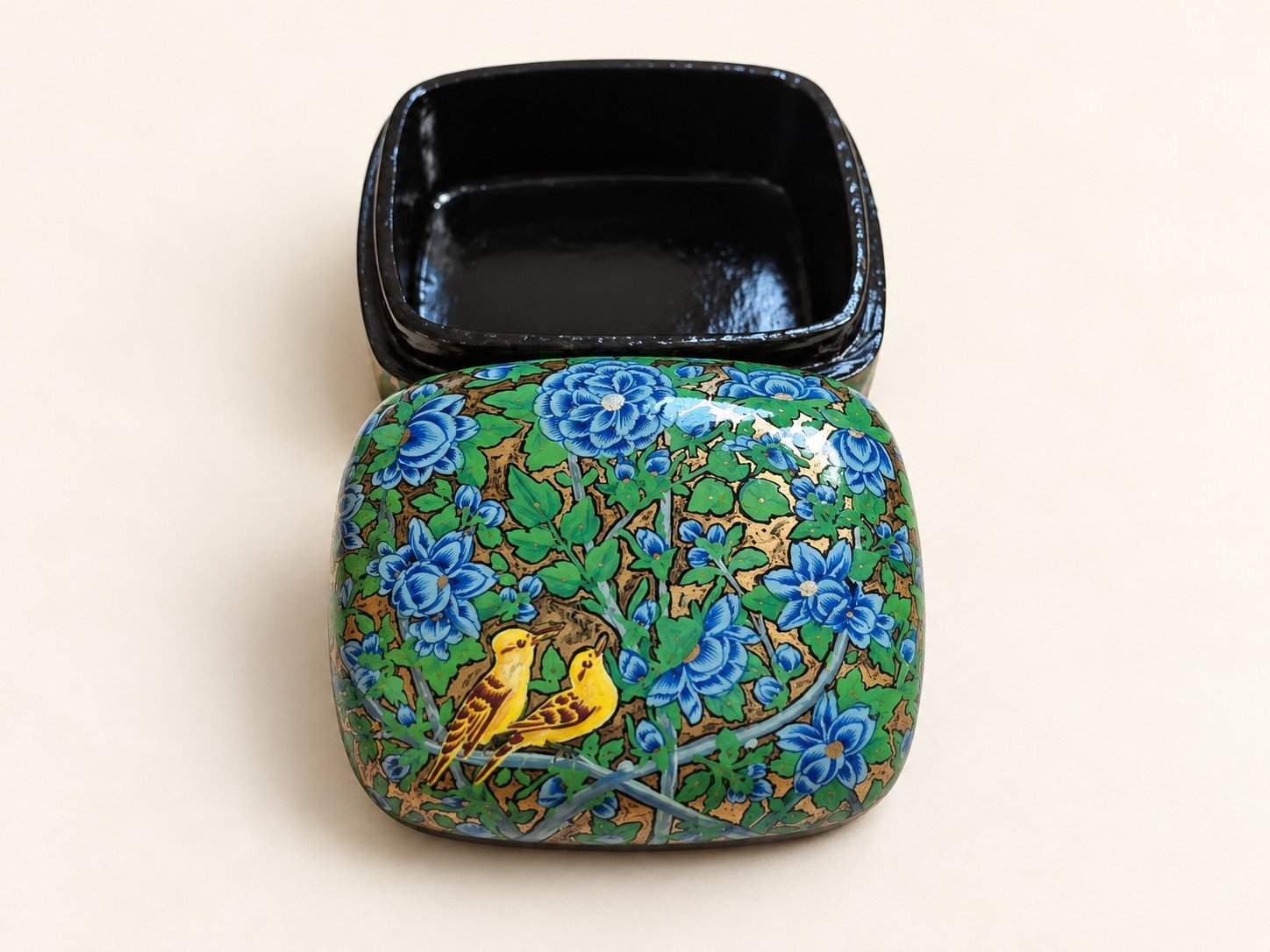 Open blue garden papier mache box with yellow songbirds on the lid beside its glossy black lacquered interior