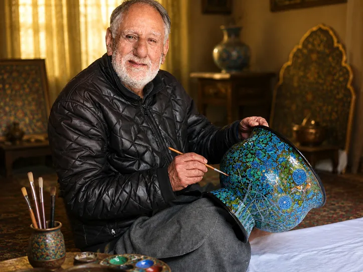 Master craftsman Nasir Hussain hand-painting a paper mache bowl in his Srinagar workshop