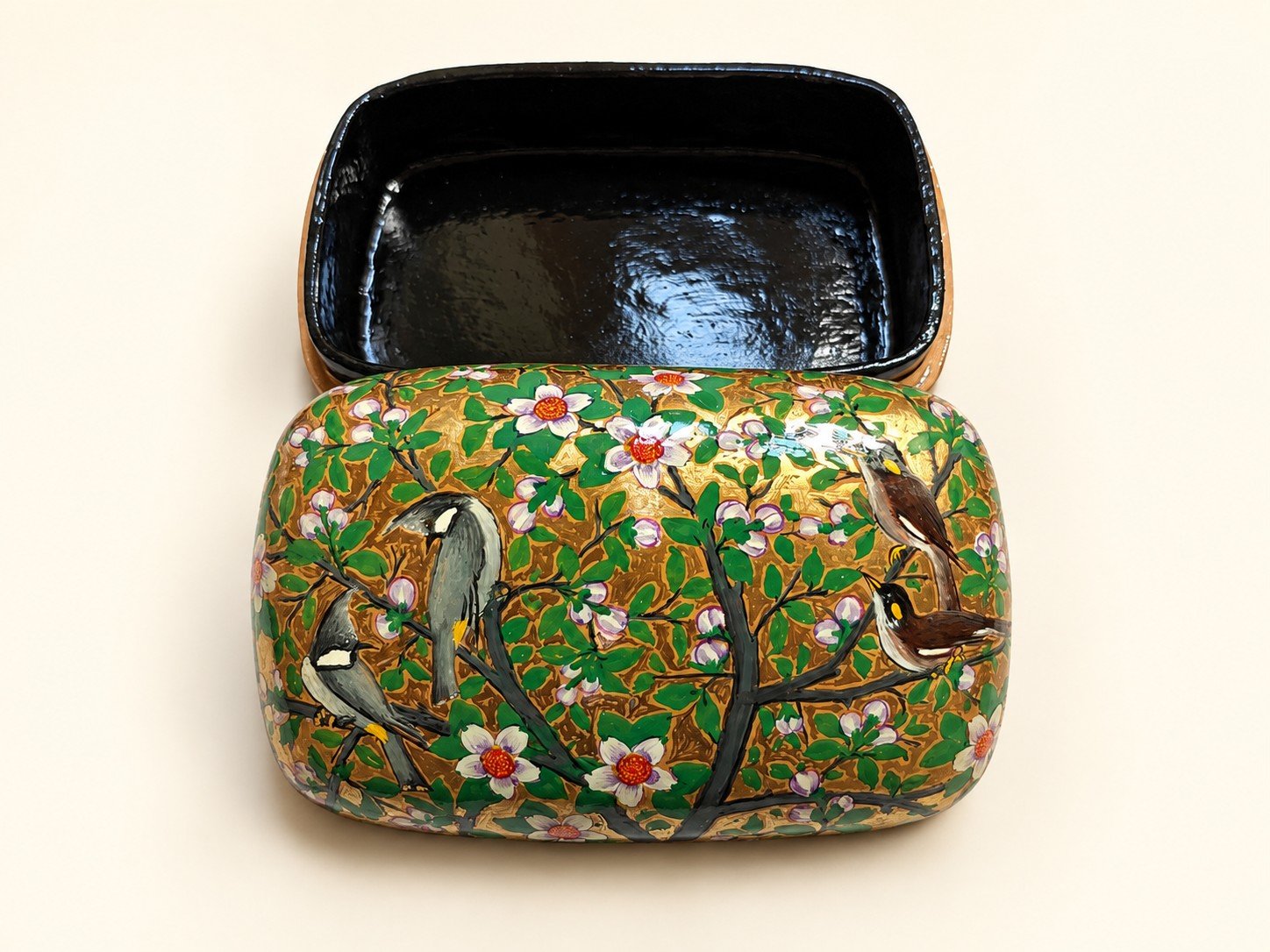 Open 7x4 inch papier mache box hand-painted with birds on flowering branches and white blossoms on green, glossy black lacquered interior
