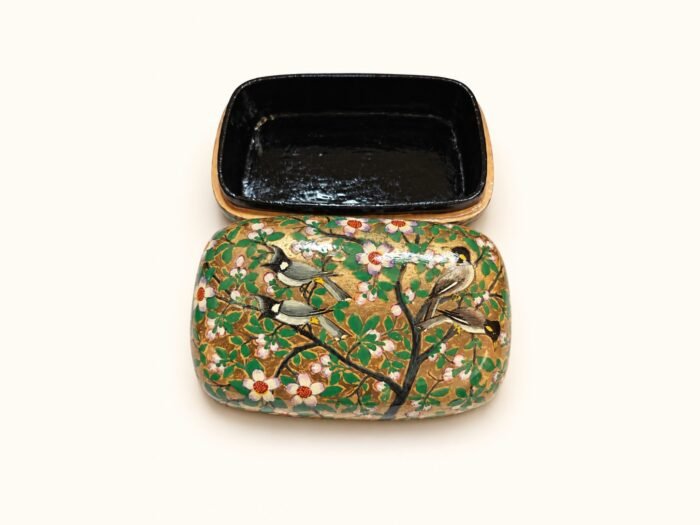 Open 7x4 inch papier mache box hand-painted with a pair of grey and white birds on a flowering branch with white blossoms on gold and green, glossy black lacquered interior