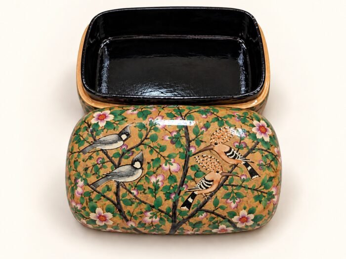Open 7x4 inch papier mache box hand-painted with grey birds on flowering branches and white blossoms on a golden background, glossy black lacquered interior