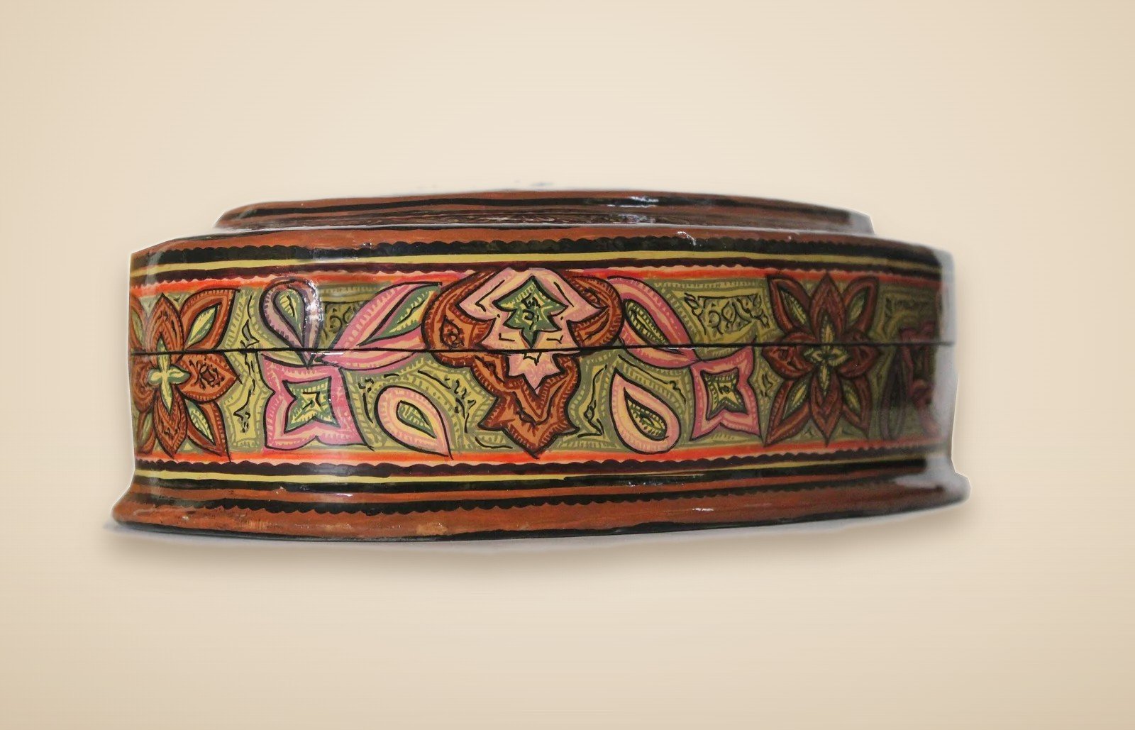 Hand-painted Kashmiri paper mache art in a paisley Mughal design, style 2, on a warm studio background