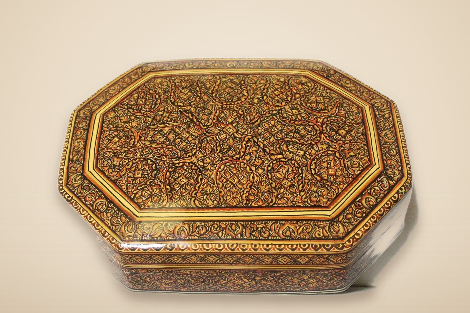Hand-painted Kashmiri paper mache art in a paisley Mughal design, style 3, on a warm studio background
