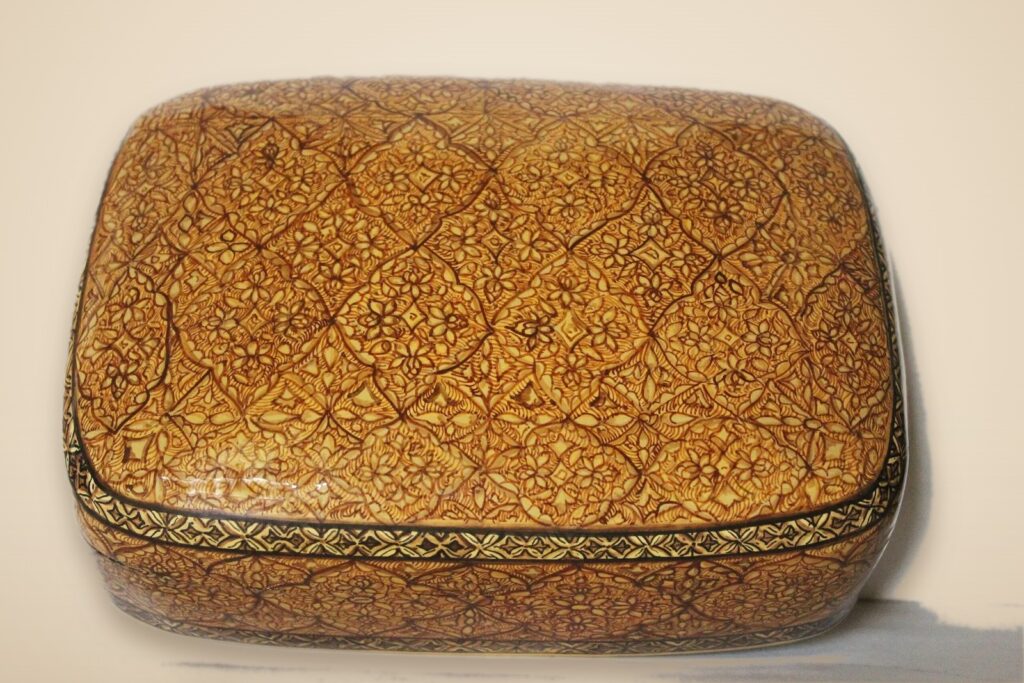 Hand-painted Kashmiri paper mache art in a paisley Mughal design, style 4, on a warm studio background