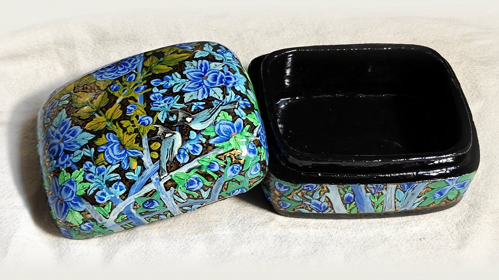 Blue Garden papier mache box No. 3 hand-painted with a pair of crested bulbuls among cobalt and sky-blue blossoms with olive leaves, real 24K gold strokes in the background, with the lid off, showing the glossy black lacquered interior