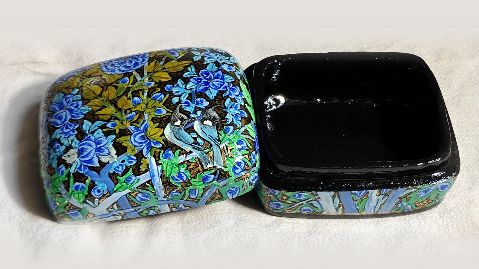 Blue Garden papier mache box No. 4 hand-painted with twin bulbuls side by side among cobalt and sky-blue blossoms with olive leaves, real 24K gold strokes in the background, with the lid off, showing the glossy black lacquered interior