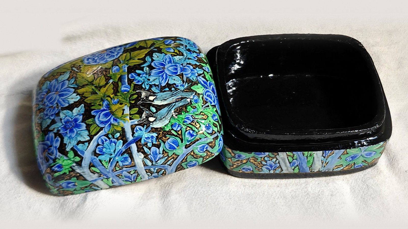 Blue Garden papier mache box No. 6 hand-painted with two bulbuls in flight among cobalt and sky-blue blossoms with olive leaves, real 24K gold strokes in the background, with the lid off, showing the glossy black lacquered interior