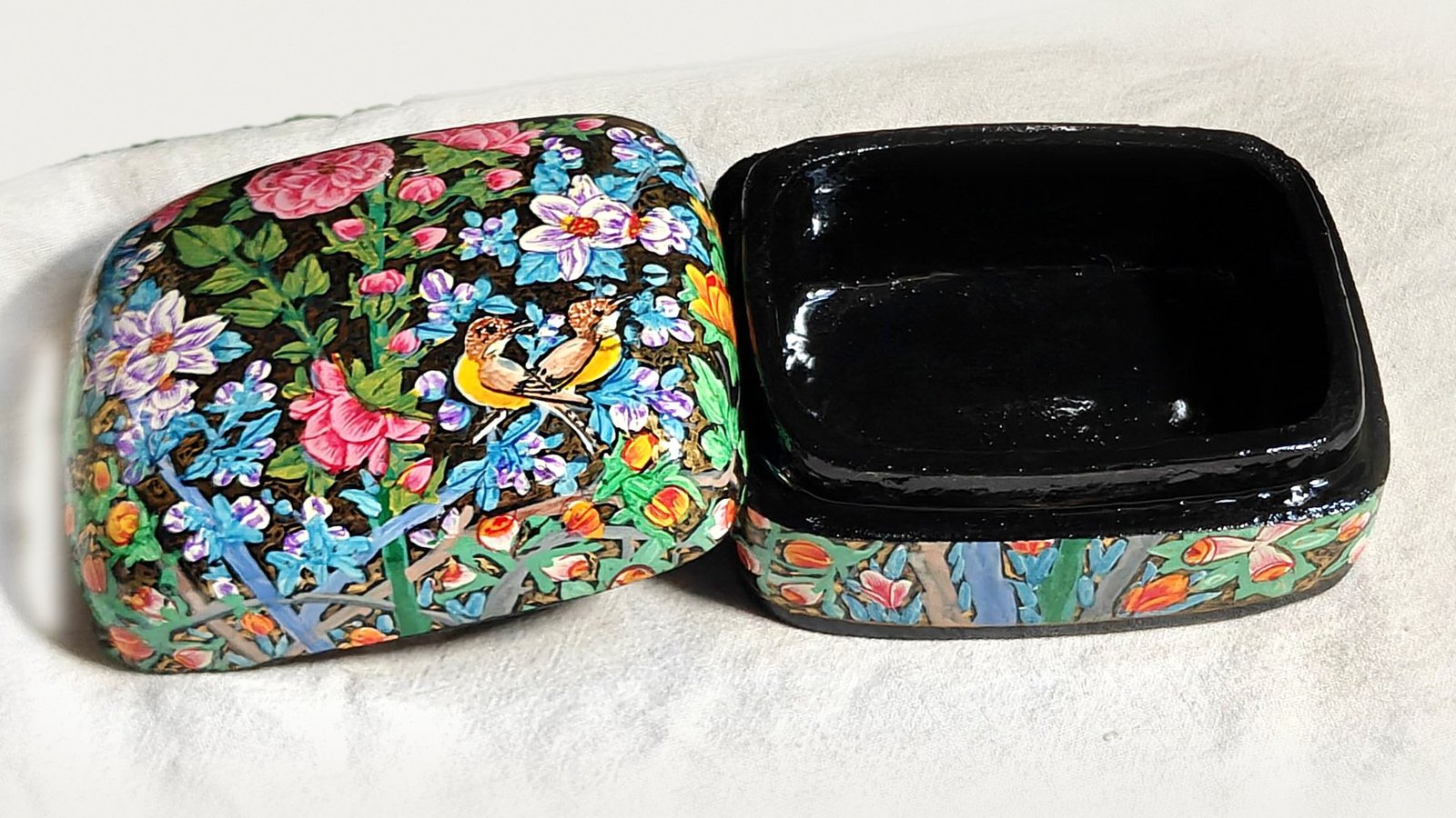 Rose Garden papier mache box No. 1 hand-painted with a pair of golden songbirds among pink roses, lilac blossoms and orange buds, real 24K gold strokes in the background, with the lid off, showing the glossy black lacquered interior