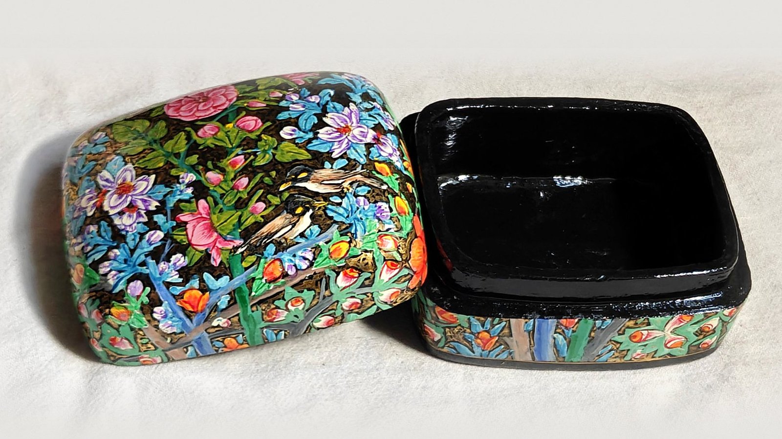 Rose Garden papier mache box No. 2 hand-painted with a pair of mynas among pink roses, lilac blossoms and orange buds, real 24K gold strokes in the background, with the lid off, showing the glossy black lacquered interior